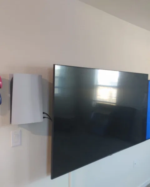 Two TVs mounted side by side with a game console and controllers