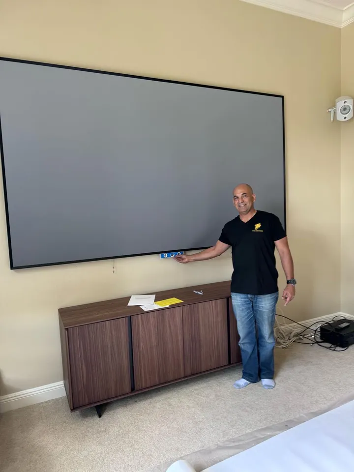 Pro Services technician leveling a large projector screen installation